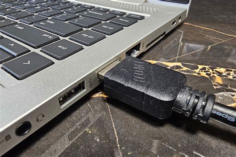 Foto van een HDMI-kabel die is aangesloten op een laptop en een tv.