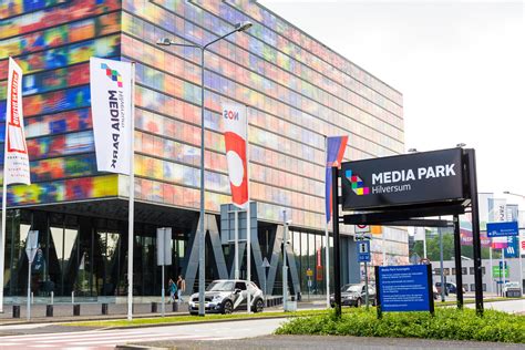 Illustratie van het Media Park in Hilversum met logo's van verschillende omroepen en facilitaire bedrijven.