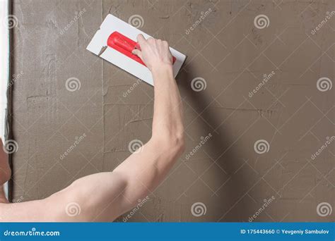 Illustratie van het aanbrengen van tegellijm met een lijmkam op de muur