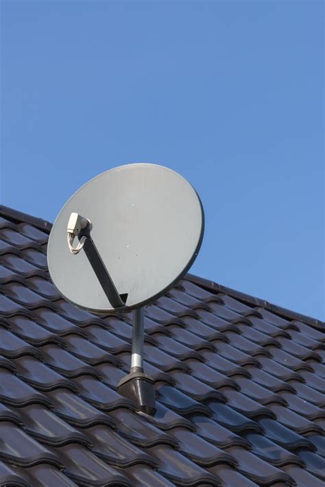 Illustratie van een monteur die een schotelantenne op een dak installeert.