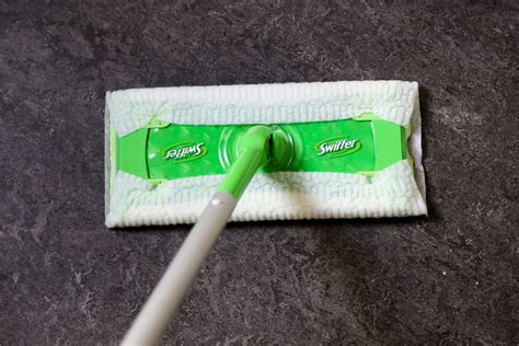 Een Swiffer vloerwisser die stof en haren van een hardhouten vloer opneemt.