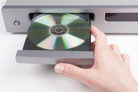 Close-up van een hand die een CD in een CD-speler plaatst, met nadruk op het tactiele aspect.