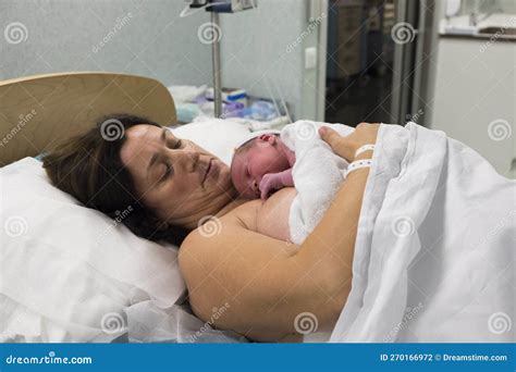 Een pasgeboren baby die op de borst van de moeder ligt, met medisch personeel op de achtergrond