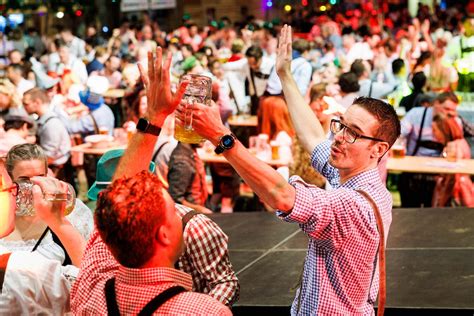 Een sfeerbeeld van een Oktoberfest met mensen die dansen en zingen.