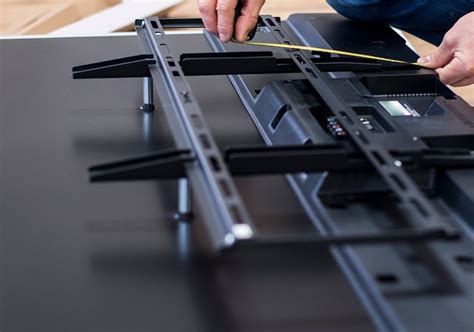 Illustratie van het bevestigen van de muurbeugel aan de achterkant van een televisie.