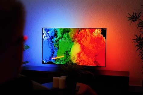 Illustratie van een Philips OLED TV met Ambilight-technologie die sfeerverlichting op de muur projecteert.