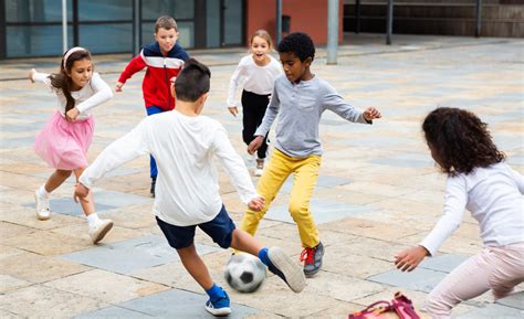 Themafoto: Een vrolijke groep kinderen die samen voetballen op een schoolplein.