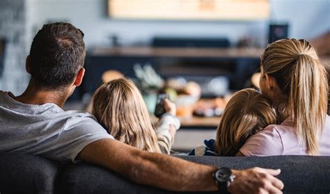 Een sfeervolle afbeelding van een koppel dat gezellig op de bank zit te kijken naar een film op Netflix, met dekentjes en snacks.