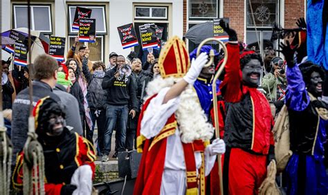 Foto van een Sinterklaasintocht met demonstranten op de achtergrond