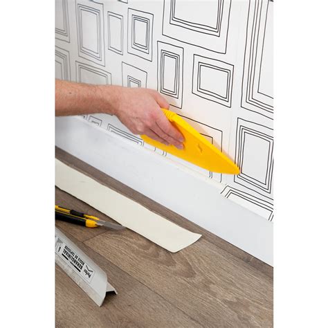 Illustratie die laat zien hoe de Perfax Behangliniaal wordt gebruikt om behang strak langs een plint af te snijden.