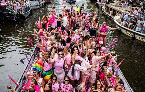 Een foto van de Canal Parade met veel boten en toeschouwers langs de grachten.