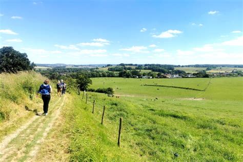 Een weids uitzicht over glooiende groene heuvels met een schilderachtig landhuis in de verte.