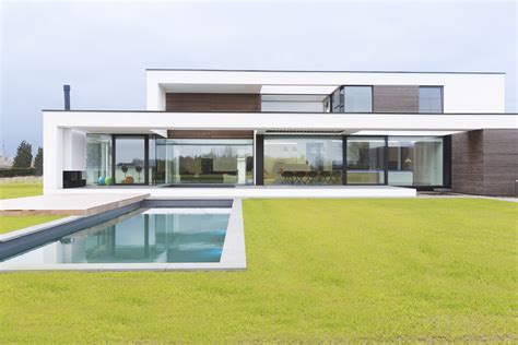 Een architectonisch ontwerp van een modern huis met veel glas en staal, gelegen aan de kust.