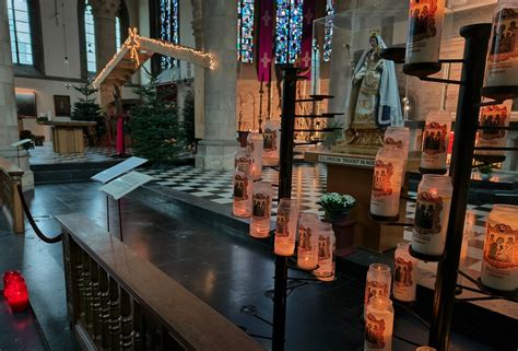 Een sfeervolle foto van een kerk interieur verlicht door kaarsen, met muzikanten op het podium.