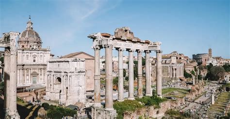 Een panoramisch shot van de Romeinse Forum met de oude ruïnes, onder een heldere blauwe hemel.