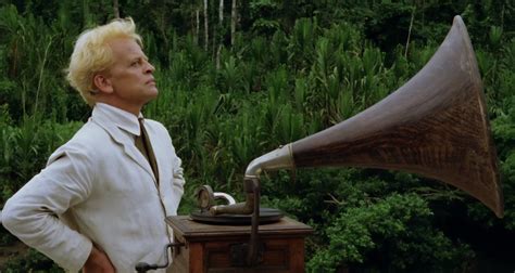 Klaus Kinski als Fitzcarraldo, met een uitdrukking van intense ambitie, in de jungle setting van de film.